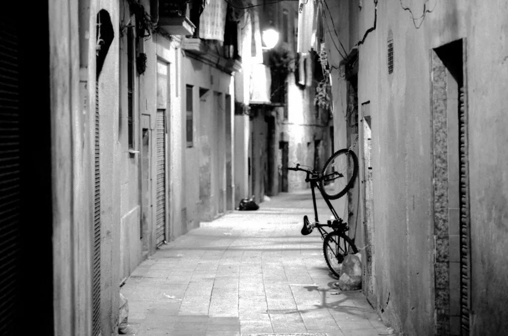 Callejón estrecho del casco antiguo de Barcelona en blanco y negro, con una bicicleta apoyada en la pared