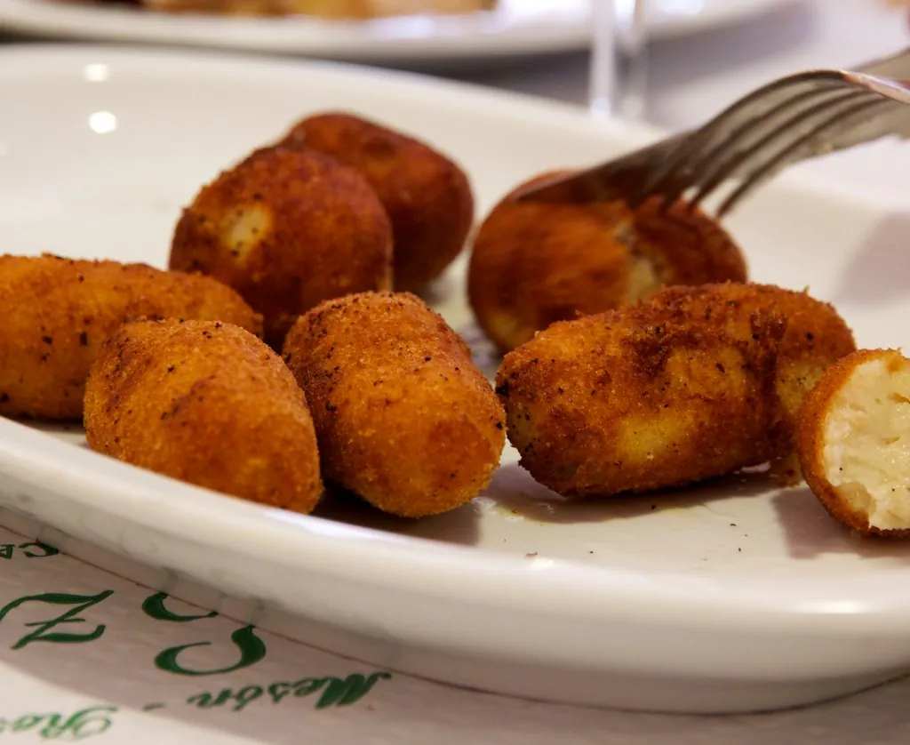 Croquetas doradas en un plato blanco, una partida por la mitad