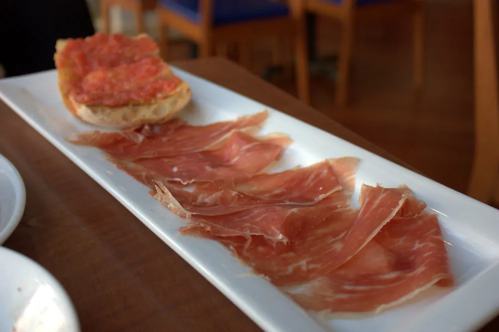 Jamón de bellota cortado a cuchillo, con pan de cristal y tomate.