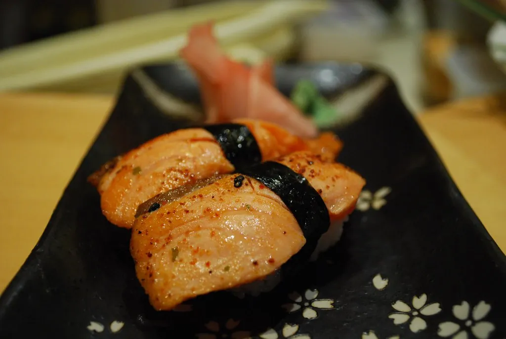 Dos nigiris de salmón flambeado sobre plato negro